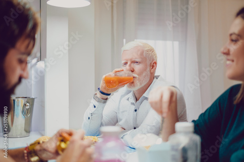 Albino man drinking juice at the dinner with friends