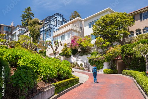 Young woman wearing backpack is walking on the Lombard Street in San Francisco, USA. Travel and adventure concept. photo