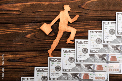 Silhouette of an employee climbing the stairs of American dollar bills on a wooden background. business, Finance. career growth.