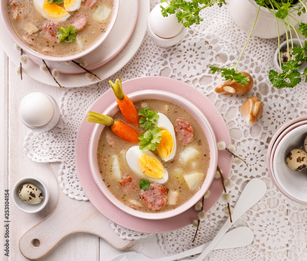 The sour soup (Żurek), polish Easter soup with the addition of sausage, hard boiled egg and vegetables in a ceramic bowl. Traditional Easter food in Poland The sour soup (Żurek), polish Easter soup with the addition of sausage, hard boiled egg and vegetables in a ceramic bowl. Traditional Easter food in Poland