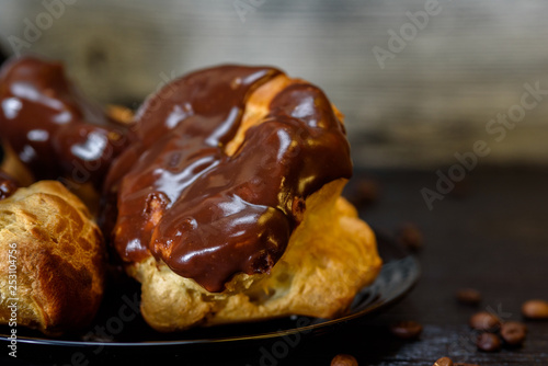 Coffee and chocolate eclairs on a wooden background