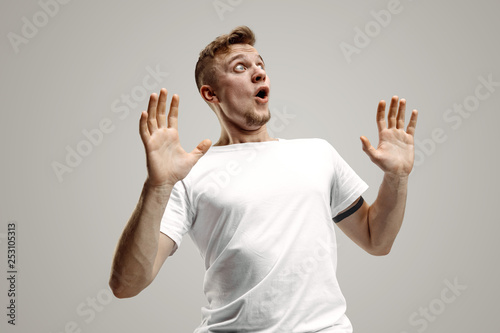 Wow. Attractive male half-length front portrait on gray studio backgroud. Young emotional surprised bearded man standing with open mouth. Human emotions, facial expression concept photo