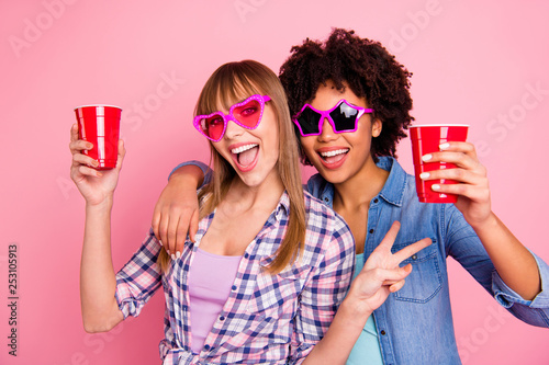 Close-up portrait of two person nice cute lovely attractive cheerful girls in casual checkered shirt showing v-sign isolated over pink pastel background
