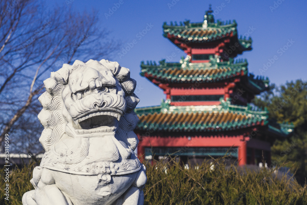 Fototapeta premium A Lion Statue Keeps Watch over an Asian-Style Building at Robert D. Ray Asian Gardens in Des Moines, Iowa
