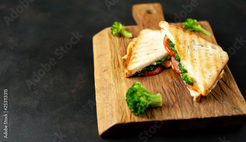 Broccoli cheese sandwiches on wooden cutting board, on concrete, slate background