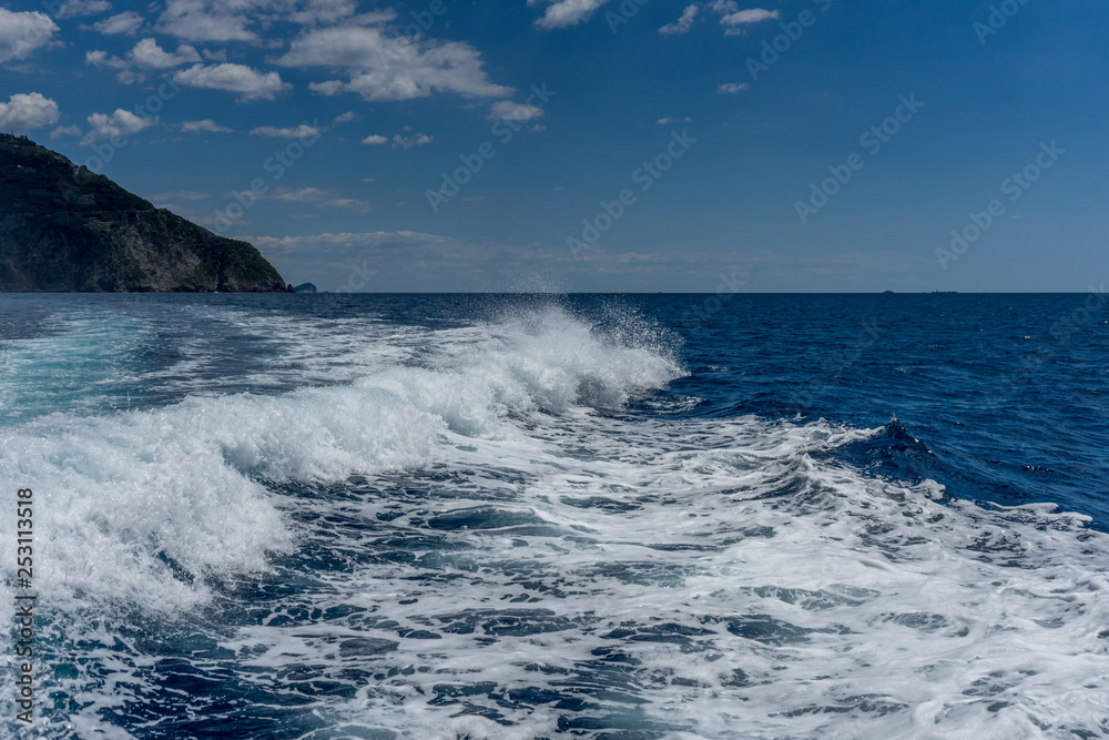 Italy, Cinque Terre, Monterosso, a man riding a wave on top of a body of water