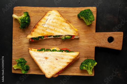Broccoli cheese sandwiches on wooden cutting board, on wooden table