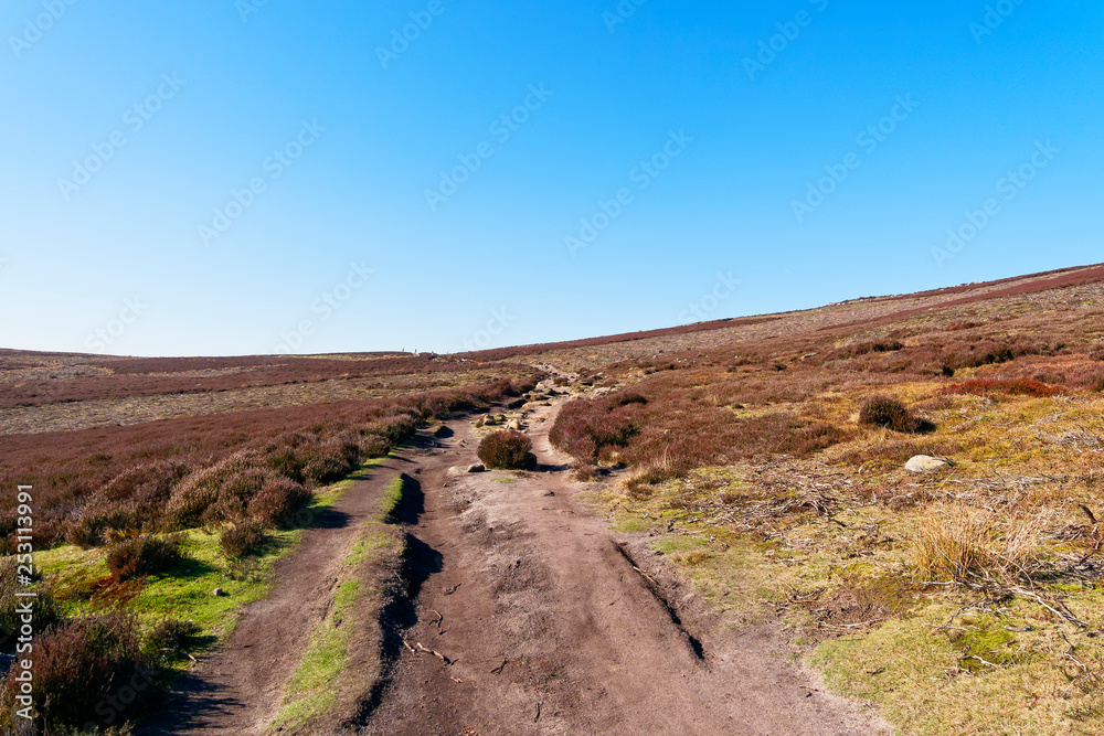 Narrow rock strewn footpath winds up hill on Derwent Moor