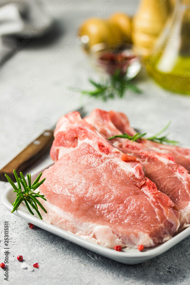 Raw pork chops, spices, herbs, olive oil. Selective focus, space for text.