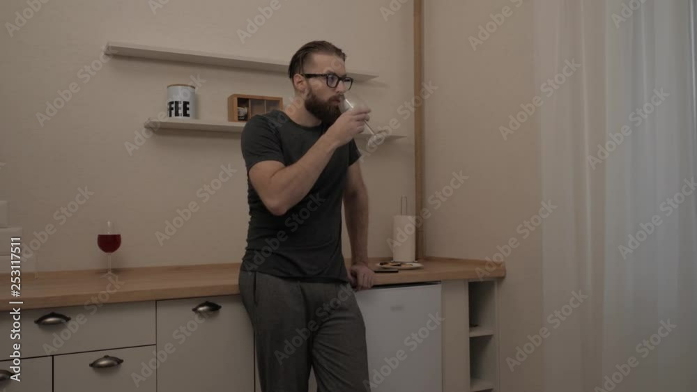 Bearded man with glass of wine at kitchen, slow motion Bearded man with glass of wine at kitchen, slow motion