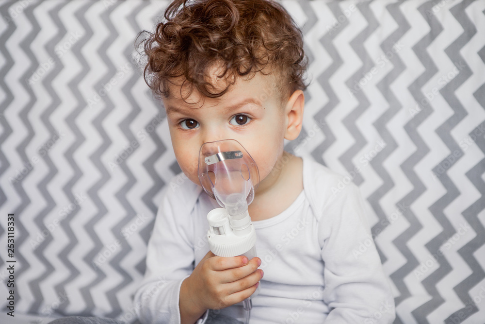 children's health. little boy with a nebulizer is sitting on a cot