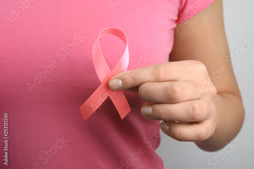 Woman holding pink ribbon, closeup. Breast cancer awareness
