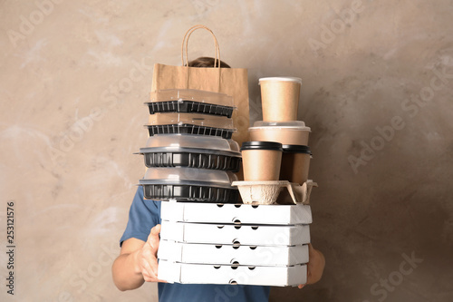 Courier with stack of orders on beige background. Food delivery service