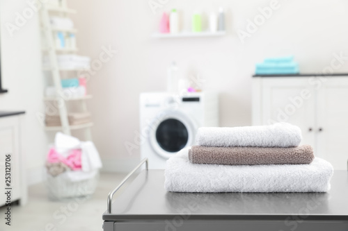 Stack of towels on table against blurred background, space for text