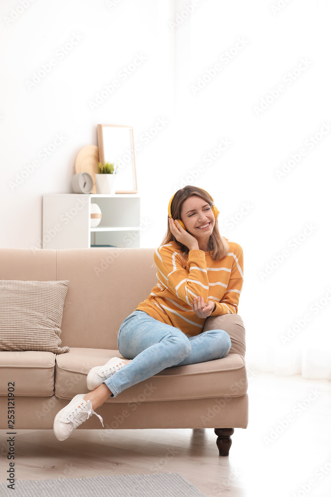 Young woman in headphones enjoying music on sofa at home Young woman in headphones enjoying music on sofa at home