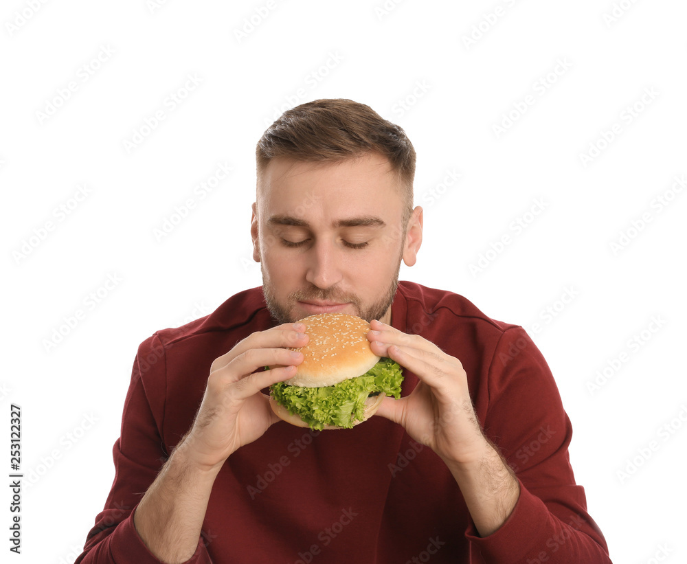 Young man eating tasty burger on white background Young man eating tasty burger on white background