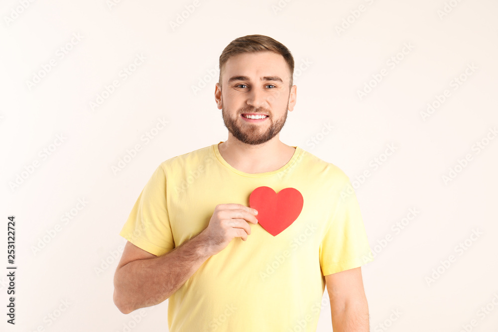 Young man with paper heart on white background Young man with paper heart on white background