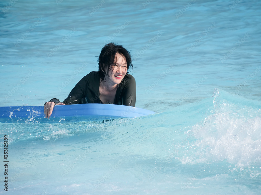 Asian woman playing wave board in water park, lifestyle concept.