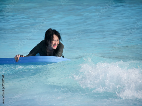 Asian woman playing wave board in water park, lifestyle concept. © nuiiko