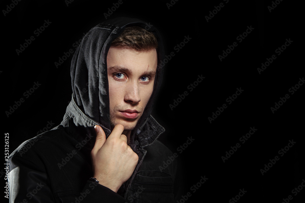 Portrait of a young man in the hood black background Portrait of a young man in the hood black background
