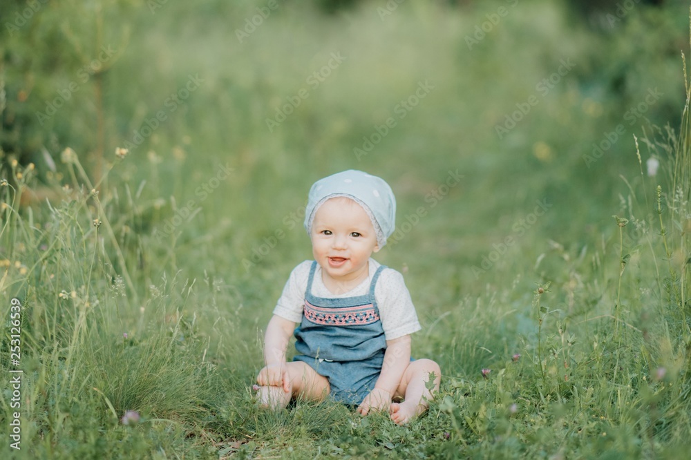 A smiling child is enjoying the nature sitting on the grass A smiling child is enjoying the nature sitting on the grass