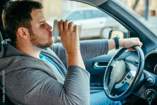 man driving car and drinking coffee