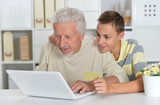Emotional boy and grandfather with a laptop