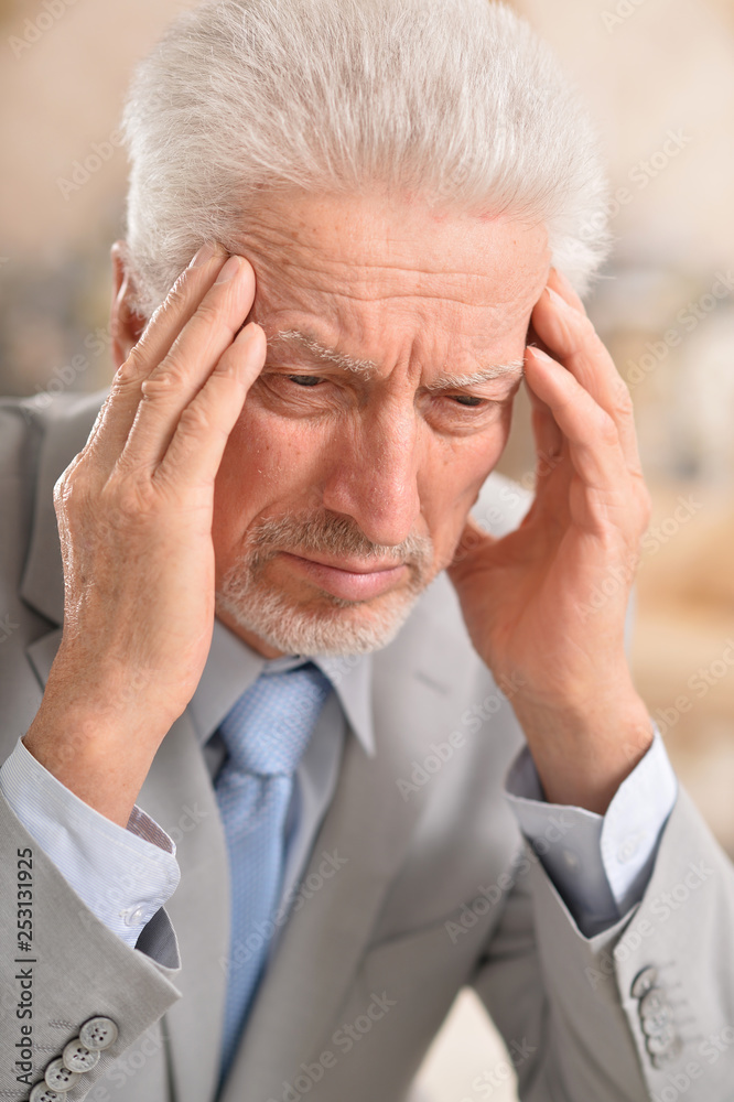 Portrait of senior man with headache holding hands on forehead at home Portrait of senior man with headache holding hands on forehead at home