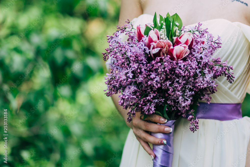 Bouquet of spring lilac flowers in young girls hands on green background. Close up picture Bouquet of spring lilac flowers in young girls hands on green background. Close up picture