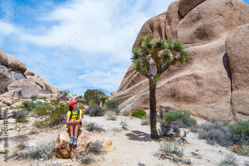 Young woman admiring a Joshua Tree in Joshua Tree National Park, California, USA. Adventure and travel concept.