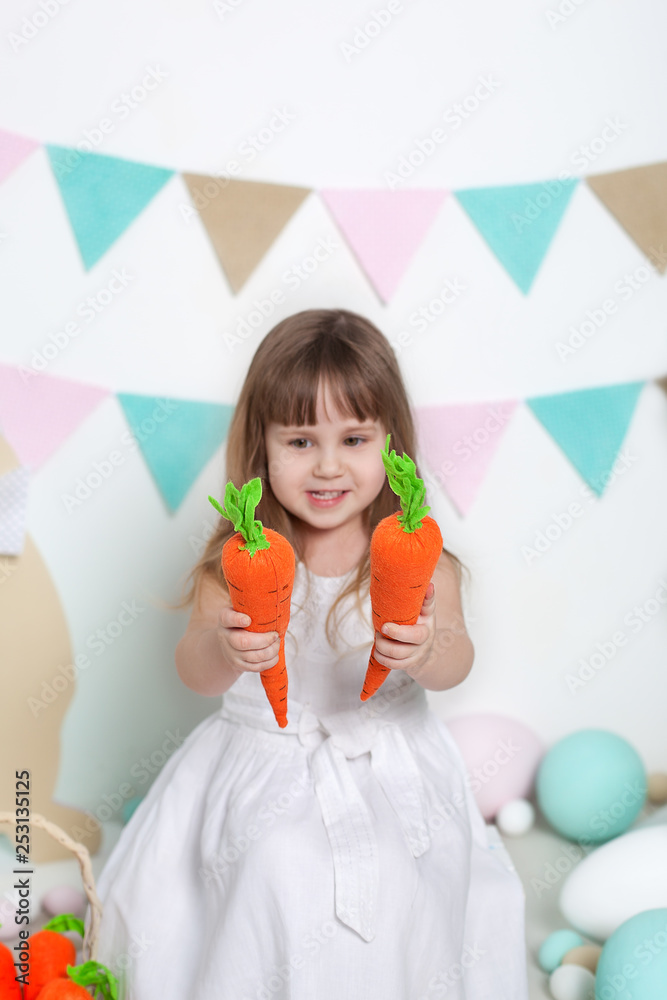 Easter 2019 Beautiful little girl in white dress sitting with Easter bunnies and carrots. Rabbit and colorful eggs. Many different colorful easter eggs, colorful easter interior. Ostrich eggs Easter 2019 Beautiful little girl in white dress sitting with Easter bunnies and carrots. Rabbit and colorful eggs. Many different colorful easter eggs, colorful easter interior. Ostrich eggs