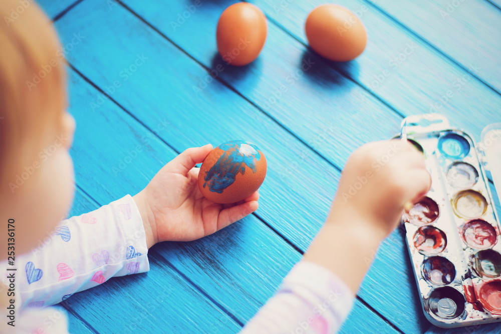 Naklejka premium Little girl painting Easter eggs. Hands doing Easter eggs. preparing for Easter