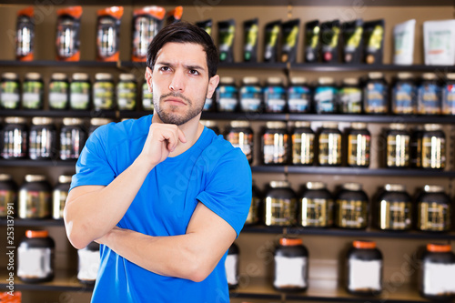 muscular man standing near shelves with sport nutrition