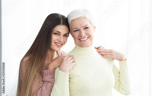 Older mom and daughter posing and looking at camera
