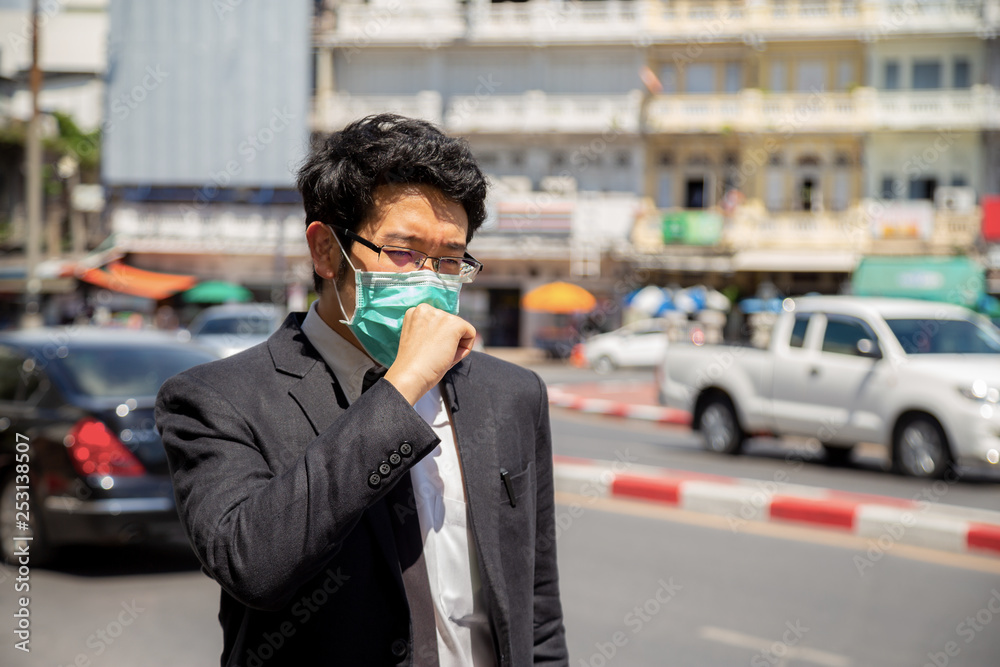 A man wearing mouth mask against air smog pollution with PM 2.5 in Bangkok city, Thailand.