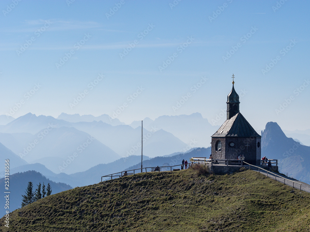 Wallberg Kapelle mit blauen Bergen im Sonnenschein, Teleaufnahme, Bayern