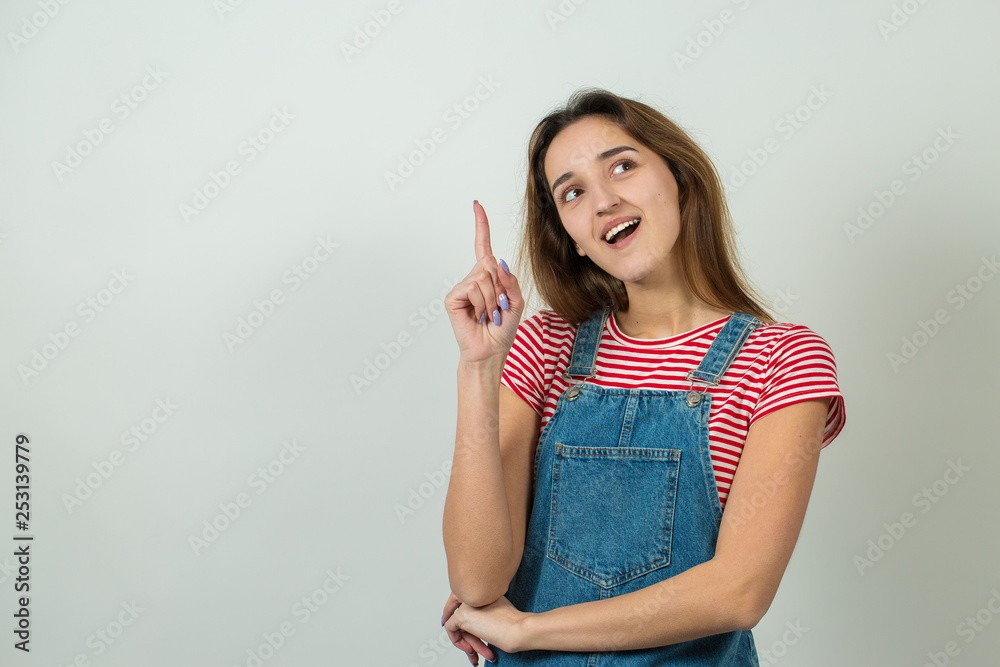 Happy young caucasian female in a striped red T-shirt pointing fingers away, showing copy space for your text. Happy young caucasian female in a striped red T-shirt pointing fingers away, showing copy space for your text.
