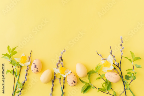 Flat lay easter composition with yellow daffodils and eggs on a yellow background
