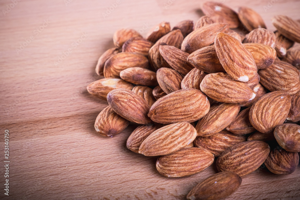 Close up pile of almonds on wooden floor,background. Close up pile of almonds on wooden floor,background.