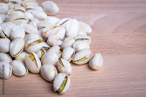 Close up Pistachio nuts with shell on wooden floor background.