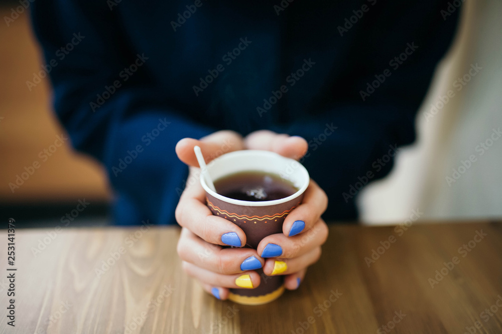 Girl in warm clothes holding a glass of coffee Girl in warm clothes holding a glass of coffee