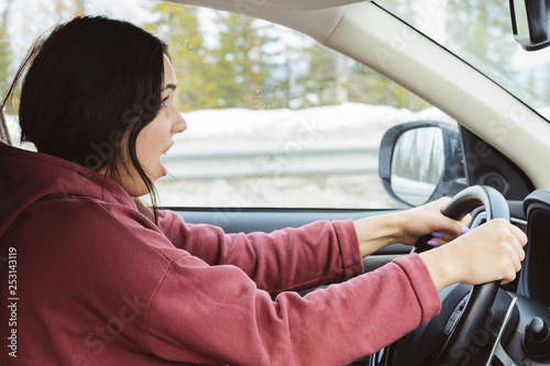 woman learning to drive a car in a sunny day on the highway. Screaming and afraid of accident. Novice driver. Hold the steering wheel tightly