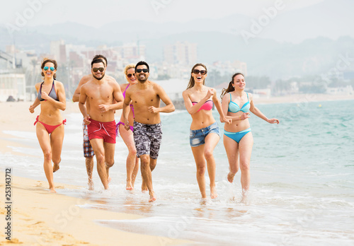 Group of laughing friends running in swimwear