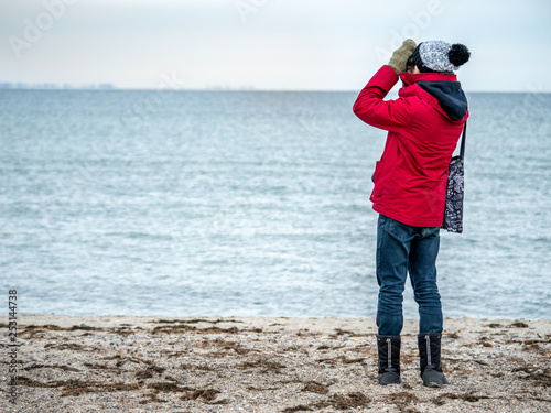 Obraz na płótnie Young man on the beach wachting birds life using telescope w salonie