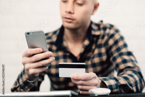 Cropped picture of man with credit card white pattern and phone photo