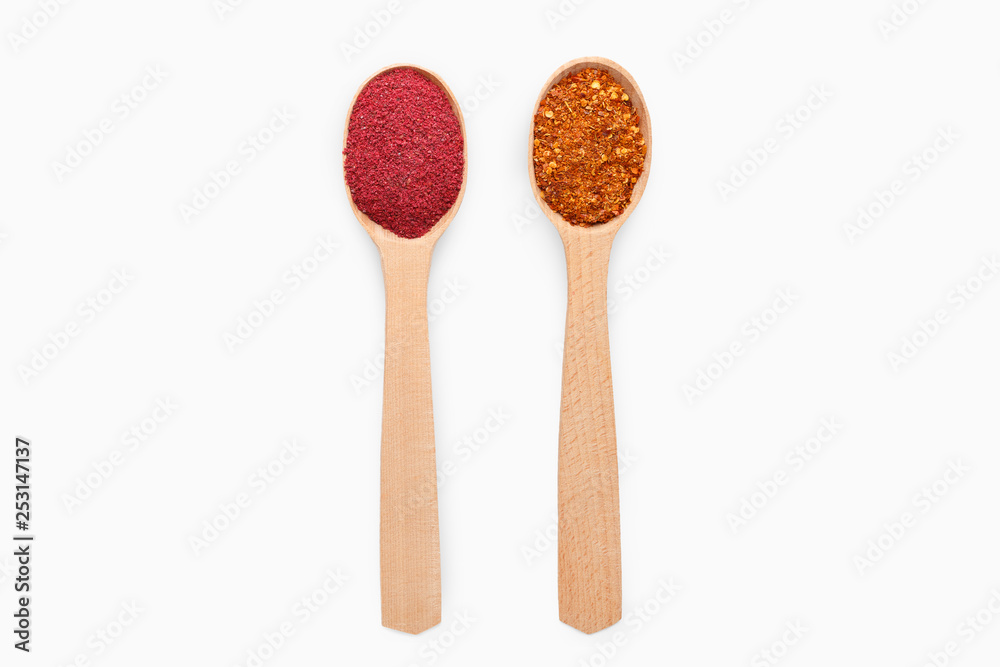 Wooden spoons with chili pepper and sumac on white Wooden spoons with chili pepper and sumac on white