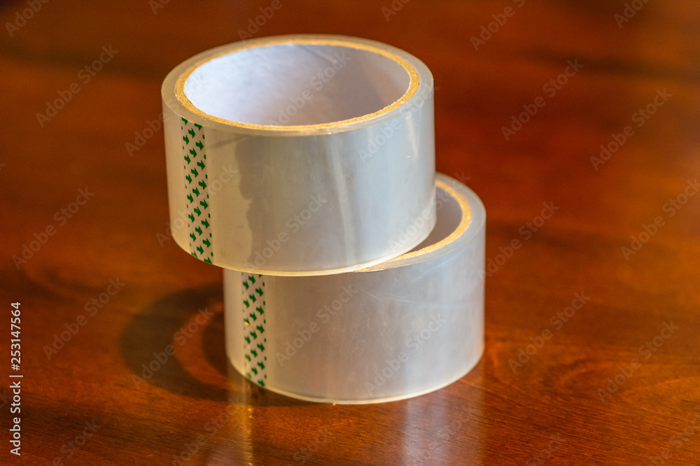 Transparent adhesive tape roll on wooden background Transparent adhesive tape roll on wooden background