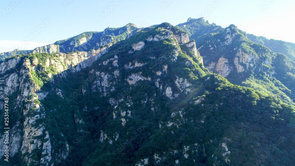 Aerial view of green mountain with river. Mountain peak with beautiful blue sky and green forest. Landscape of mountain in natural reserve park. Miyun, Beijing, China.