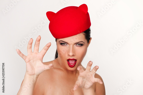 Charming and flirting girl in a funny red hat, the image of a playful cat