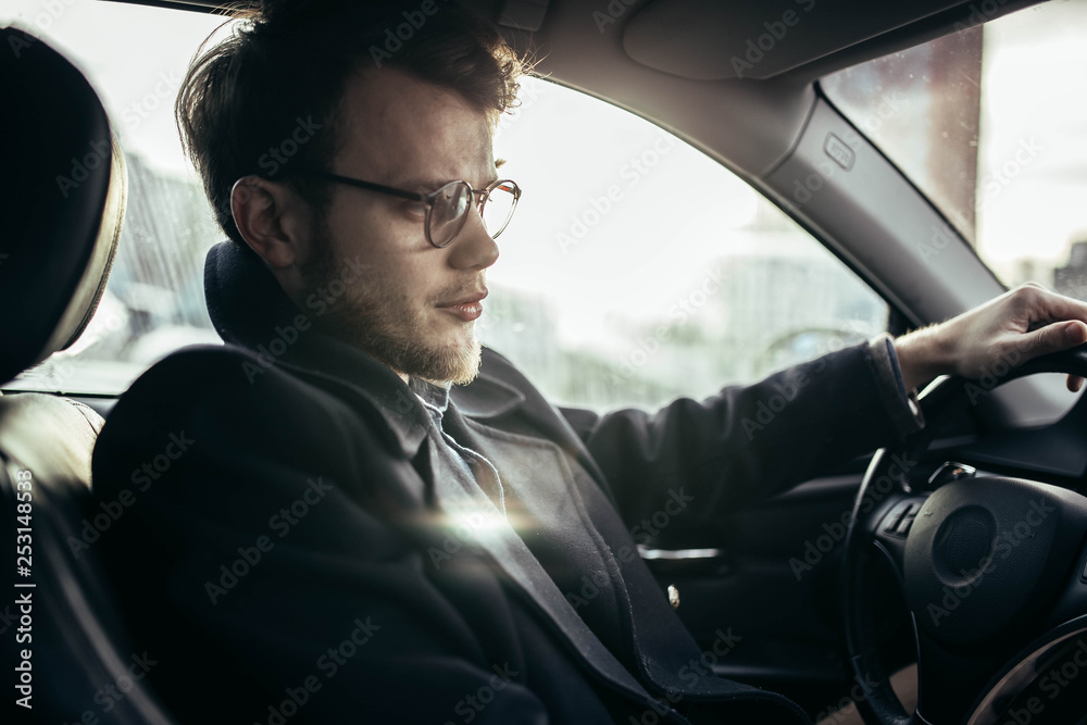 man hipster with a beard in glasses a driver of a modern car in salty weather. man hipster with a beard in glasses a driver of a modern car in salty weather.